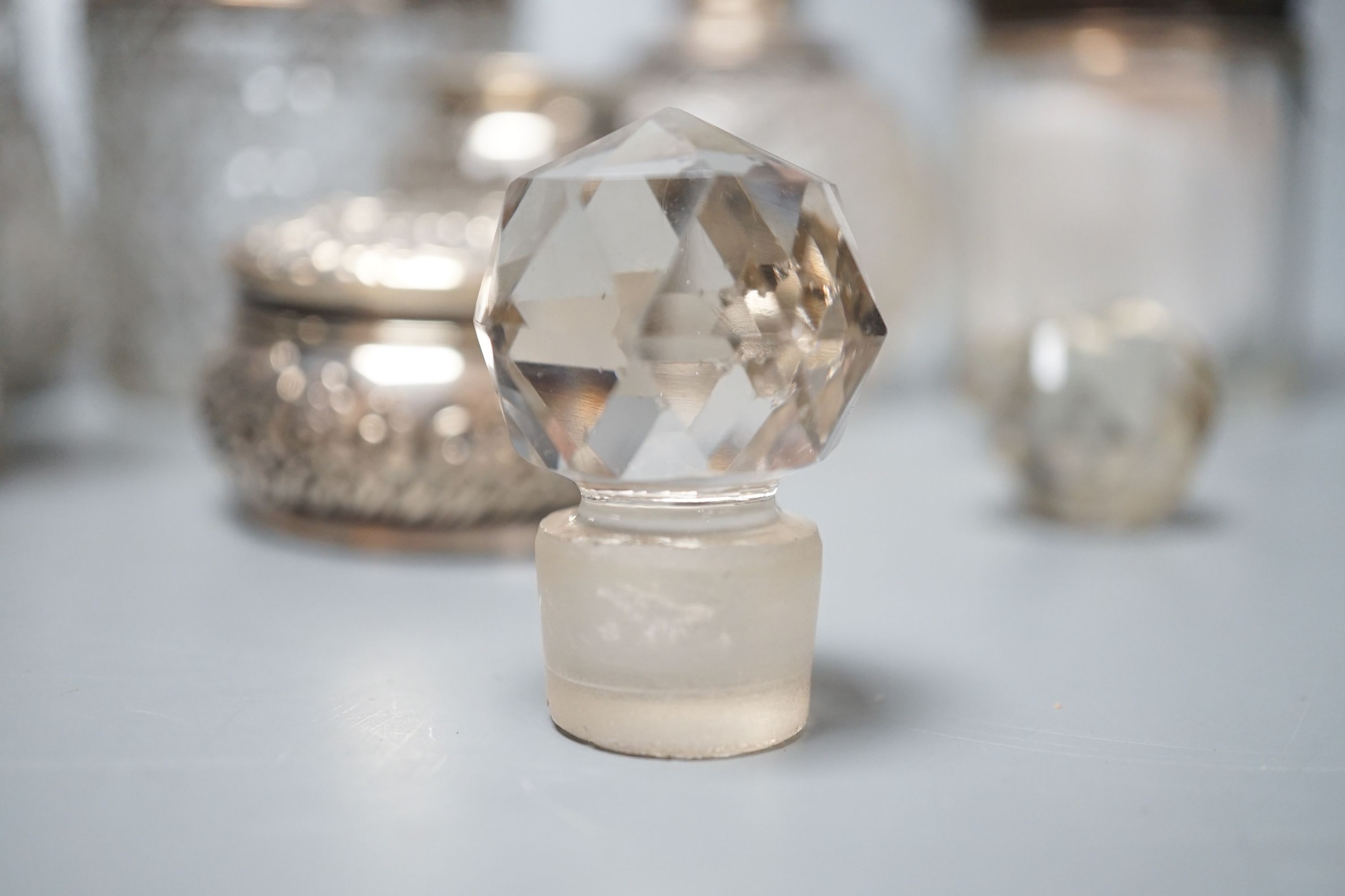 A circular embossed silver box and six silver mounted glass toilet bottles.